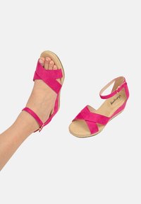 Sandali in suede fucsia con design a strap incrociati, cinturino alla caviglia e soletta beige. Presentano un tacco basso per un comfort maggiore.