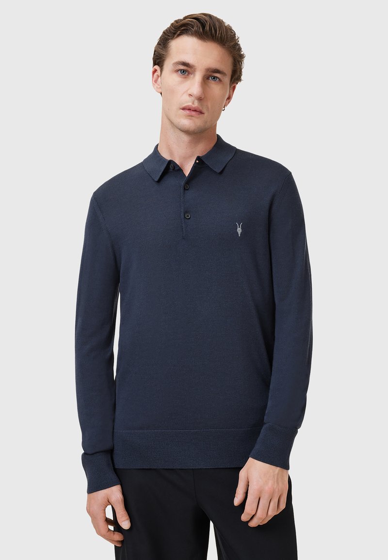 Camisa polo de manga larga en color navy, fabricada en punto, con cuello tipo polo, tapeta de cinco botones y pequeño logotipo en el lado izquierdo del pecho.