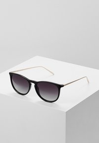 Sorte solbriller med gradientlinser, gylne metalarmar, rundet firkantet fasong, lett plastisk ramme, minimalistisk design.