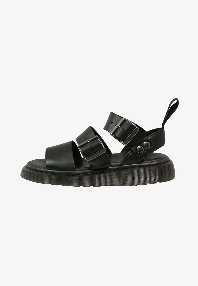 Sandale en cuir noir avec deux brides à boucle, semelle épaisse et languette au talon, conçue pour un usage décontracté.