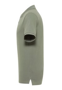 Koszulka polo, oliwkowa, krótki rękaw, klasyczny kołnierzyk, rozcięcia po bokach u dołu, wykonana z gładkiej tkaniny bawełnianej. Brak widocznych wzorów lub logo.