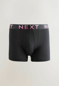 Pantalones cortos de boxeo negros con un diseño ajustado. La cinturilla elástica presenta el logo rosa de "NEXT". Textura suave con una abertura frontal.