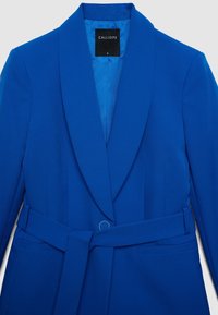 Blue tailored blazer with wide lapels, fabric belt with metal ring, and two front welt pockets, size small with CALLIOPE label.