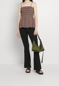 Hvězdicový vzor v tmavých odstínech, smocked korzet, tenké ramínka, v kombinaci s černými rozšířenými kalhotami a zelenou kabelkou přes rameno. Obuv: černé sandály.