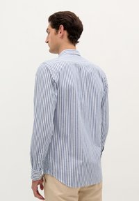 Gestreiftes Hemd in Blau und Weiß, mit einem klassischen Kragen, langen Ärmeln und einem abgerundeten Saum. Hergestellt aus leichtem Baumwollstoff.