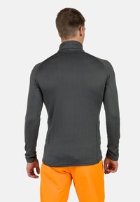Camicia aderente a maniche lunghe di colore grigio scuro con un motivo testurizzato; colletto alto con spalle senza cuciture e aperture per il pollice.