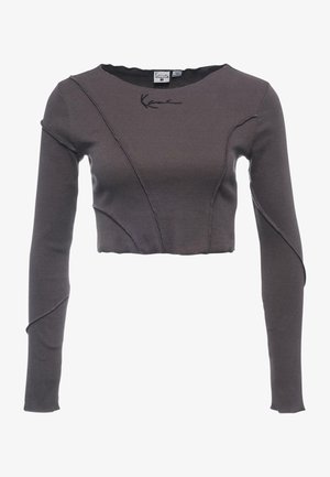 Tmavě šedý krátký top s dlouhými rukávy, prošívanými švy, kulatým výstřihem a malým černým signovaným detailem u límce.