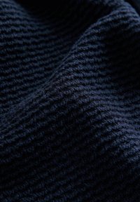Tissu texturé marine avec un motif tissé, présentant une surface douce et légèrement duveteuse ainsi qu'une couleur riche et profonde. Convient pour les vêtements ou le rembourrage.