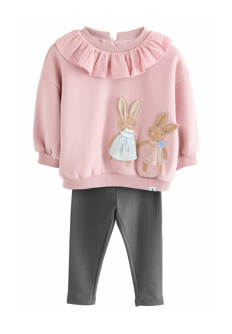 Sweatshirt rose avec un col volanté arborant deux lapins brodés, associé à des leggings gris côtelés. Tissu doux, design décontracté.