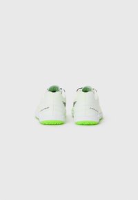 Scarpe da ginnastica bianche con texture liscia, dotate di suole e accenti sul tallone di colore verde neon, e con un sottile motivo decorativo sulla parte superiore.