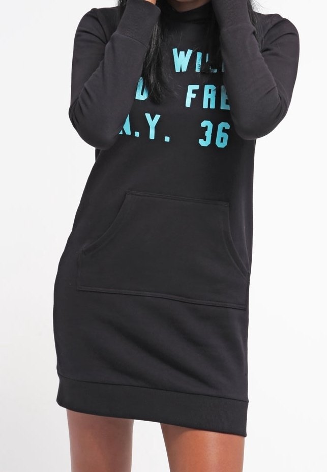 Kobieta w czarnej sukience z długim rękawem typu hoodie, z przednią kieszenią, z jasnoniebieskim napisem częściowo brzmiącym "WILD FREE N.Y. 36".