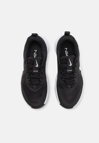 Sorte atletik sko med meshuprør, polstret sål og markant hvid Nike swoosh. Har snørebånd og "JUST DO IT" på tungen.