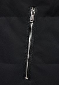 Czarny zamek błyskawiczny z metalowymi zębami i suwakiem na teksturowanej tkaninie, z matowym wykończeniem i eleganckim, minimalistycznym designem.