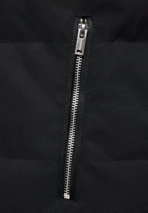 Czarny zamek błyskawiczny z metalowymi zębami i suwakiem na teksturowanej tkaninie, z matowym wykończeniem i eleganckim, minimalistycznym designem.