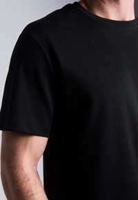 Zwart T-shirt met korte mouwen in een gladde stof, met een ronde halslijn en een nette afwerking langs de mouwen en de onderrand.
