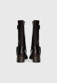 Braune Lederstiefeletten mit elegantem Design, mit Schnallenakzenten, leichtem Absatz und glatter Textur. Die Rückansicht zeigt die Höhe und Passform.
