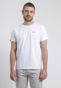 T-shirt en coton blanc avec col rond, manches courtes, présentant un petit logo multicolore sur la poitrine gauche et un design décontracté.