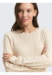 Beige gerippter Pullover mit Rundhalsausschnitt und langen Ärmeln, der eine weiche Textur und eine lockere Passform aufweist.