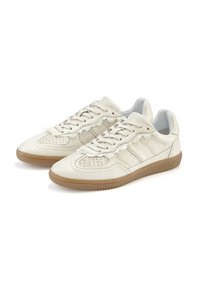 Cream-colored leather sneakers with a perforated toe, textured detailing, and a gum rubber sole. Features a lace-up closure and subtle side stripes.