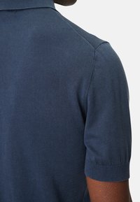 Námořnickomodré pletené polo tričko s krátkými rukávy, s hladkou strukturou a skládacím límcem; zobrazuje detaily zadní části a manžety rukávů.