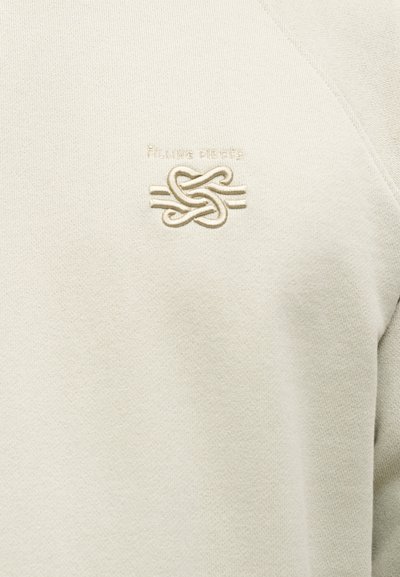 Ανοιχτό μπεζ φούτερ με απαλής υφής ύφασμα, που διαθέτει κεντημένο λογότυπο και περίτεχνο σχέδιο κόμπου στο ίδιο χρώμα. Απλό, με στρογγυλή λαιμόκοψη.