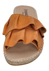 Orange suede slide sandal featuring a double-layered ruffle design, beige woven sole, and stitched detailing around the edges.