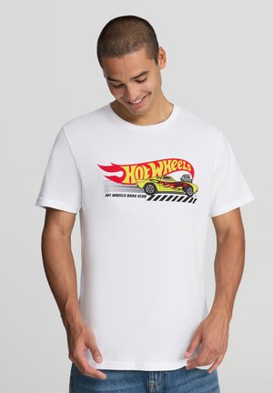 T-shirt bianca in cotone con una grafica colorata "Hot Wheels" che presenta un'auto stilizzata e un design di fiamme. Maniche corte, collo girocollo, vestibilità comoda.