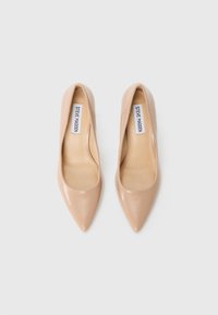Pumps nude din piele cu vârf ascuțit, cu o textură netedă, căptușeală interioară și eticheta brandului vizibilă pe branț. Proiectate pentru o potrivire elegantă.