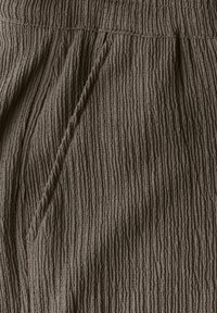 Geweven stof in donkerbruin, met verticale strepen. Inclusief elastische tailleband en een zijzakdetail. Zacht, gekreukt uiterlijk.