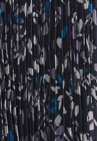 Fałdowana tkanina na ciemnym tle z motywem kwiatowym w odcieniach srebra, fioletu i niebieskiego, tworząca teksturowany wygląd.