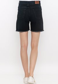 Zwarte denim shorts met rafelige zoom, voorzien van twee achterzakken en een leren merkembleem op de tailleband.