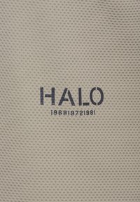 Beżowa tkanina teksturowa z napisem "HALO" w ciemnoniebieskim nad szczegółami numerycznymi "196819721981". Delikatne perforacje w całym materiale.