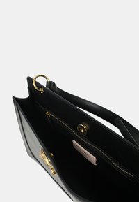 Borsa a mano in pelle nera con forma strutturata, hardware dorato, manico superiore, tasca interna con zip e etichetta del marchio visibile all'interno.