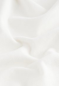 White textured fabric with a soft, smooth surface, displaying light creases and folds, suggesting a lightweight material.