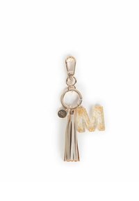 Portachiavi in oro lucido con una lettera "M" in resina glitterata, un pon-pon in pelle argentata e un attacco circolare con una piccola etichetta.