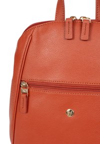 Oranje leren handtas met een gestructureerde afwerking, dubbele ritssluiting, een voorkantvak met een gouden ritssluiting en een reliëf logo-detail.