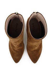 Stivaletti alla caviglia in suede marrone con punta affusolata, superficie liscia e chiusura con zip, caratterizzati da un interno morbido e un branding minimale.