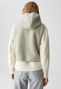 Gekürzter Hoodie, grüner Fleece-Rücken, weiche cremefarbene Zopfmusterärmel, gerippter Saum, kapuzenförmiges Design, nahtloser Texturenkontrast.