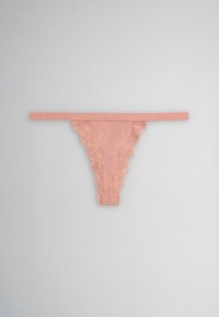 Light pink women's thong underwear with floral lace trim on a plain light gray background.