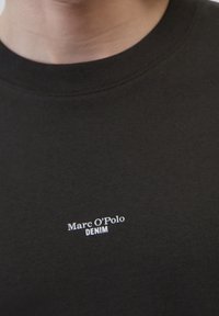 Sort bomulds T-shirt med rund hals og hvid tekstbranding "Marc O'Polo DENIM" placeret på brystet.