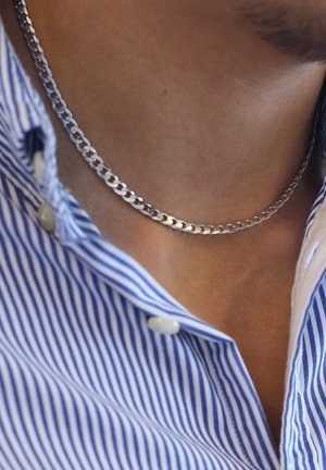 Zilveren kettinghalsketting getoond om de nek, met vergrendelde schakels en een gepolijste afwerking, gecombineerd met een blauw-wit gestreept shirt.