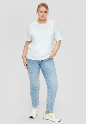 White short-sleeve t-shirt paired with light blue denim jeans. The outfit is completed with white sneakers featuring gray accents.
