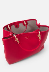 Czerwona skórzana torba typu tote z dodatkami w kolorze złotym. Otwarta góra, szara podszewka wewnętrzna i usztywniony kształt. Posiada podwójne uchwyty oraz detal z logo.