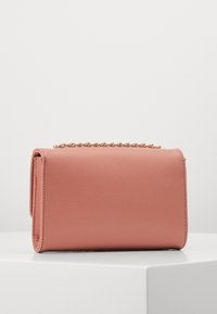 Rosa texturerad läderclutch med en guldkedjeakcent ovanpå. Den har en rektangulär form och en minimalistisk design.