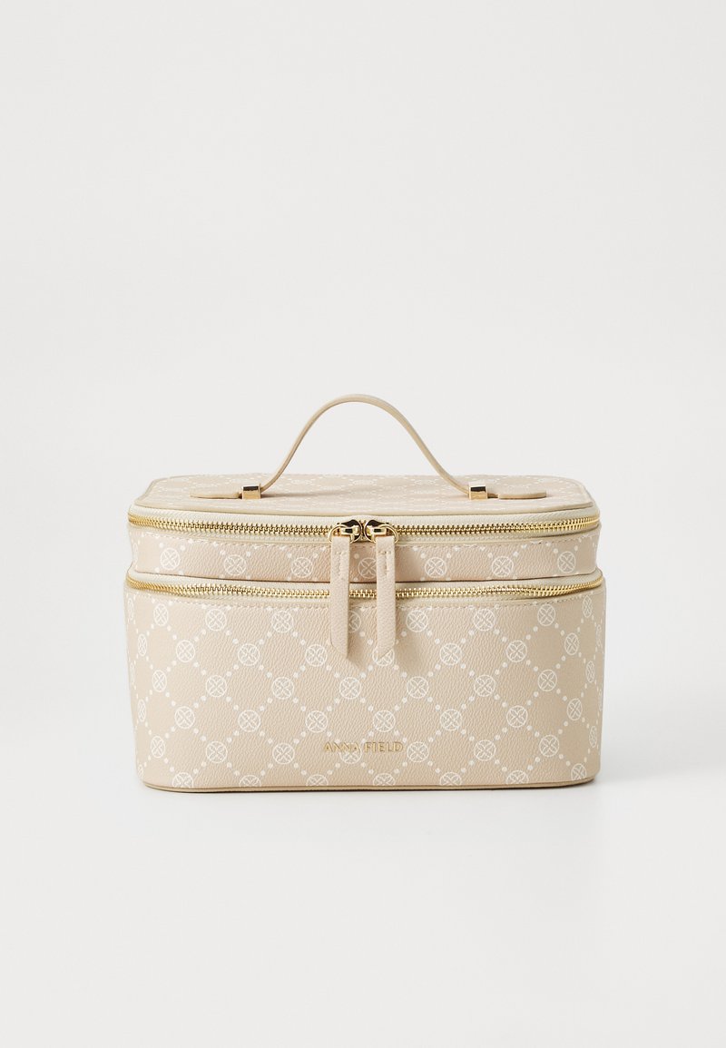 Beige kosmetikväska med texturerad yta, guldfärgad hårdvara, dubbel dragkedjestängning och ett subtilt mönster. Har ett handtag på toppen för bärande.