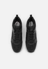 Černé sportovní tenisky s síťovinovým svrškem, hladkými syntetickými překrytími a integrovaným systémem šněrování. Obsahují bílou gumovou podrážku.