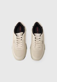 Beige mesh sneakers med kremfargede snørebånd, rund tå og svarte detaljer på hælen og fôret. Logo på siden i diskret grå.