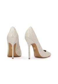 Bele visoke pete so opremljene z teksturirano, reptilsko podobno površino, so s koničastimi nosovi in tankimi stiletto petami. Zlata logotipna podrobnost na notranji strani.