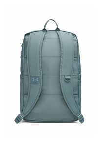 Light teal padded backpack with adjustable straps, side pockets, and logo patch. Features smooth texture and minimalistic design.