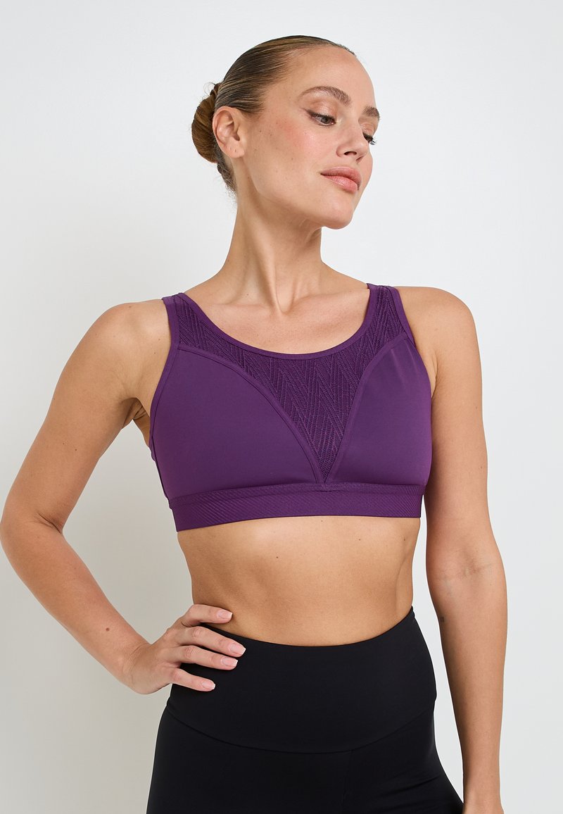 Reggiseno sportivo viola con un design geometrico testurizzato nella parte anteriore, spalline larghe e un elastico di supporto sotto il seno.